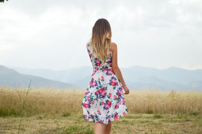 女人穿着白色、紫色和粉红色的花裙子站在布朗叶草白天
